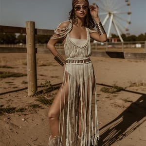 Puede incluir: Vestido de macram&eacute; color crema con flecos y detalles de cuentas. El atuendo incluye botas a juego, un pa&ntilde;uelo estampado y gafas de sol. Una modelo posa frente a una noria, creando un ambiente bohemio.