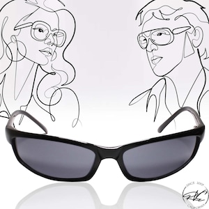 May include: Black sunglasses with a rectangular frame and dark gray lenses. The sunglasses are reflected in a shiny surface.