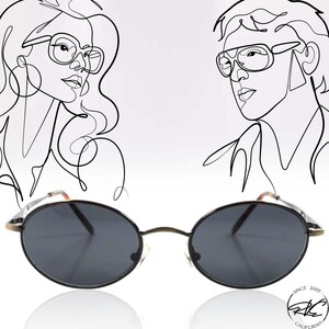 May include: Oval-shaped sunglasses with dark lenses and a thin, gold-colored frame. The image features line art illustrations of two faces wearing glasses. The sunglasses are reflected on a white surface. The text "SINCE 2005 CALIFORNIA" is visible.