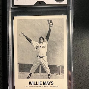 Op de afbeelding: Zwart-wit honkbalkaart van Willie Mays, 1977 TCMA, beoordeeld met Mint 9. De kaart toont Mays in een Giants-uniform, een bal vangend. Tekst bevat "WILLIE MAYS" en "OUTFIELDER-NEW YORK GIANTS".