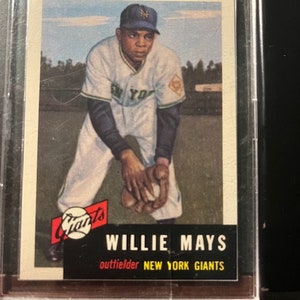 May include: A vintage baseball card featuring Willie Mays, an outfielder for the New York Giants. The card has a red and black "Giants" logo with a baseball in the center. The card features a color illustration of Willie Mays in a white and green baseball uniform with the text "New York" on the front. The card has a white background with a black border.
