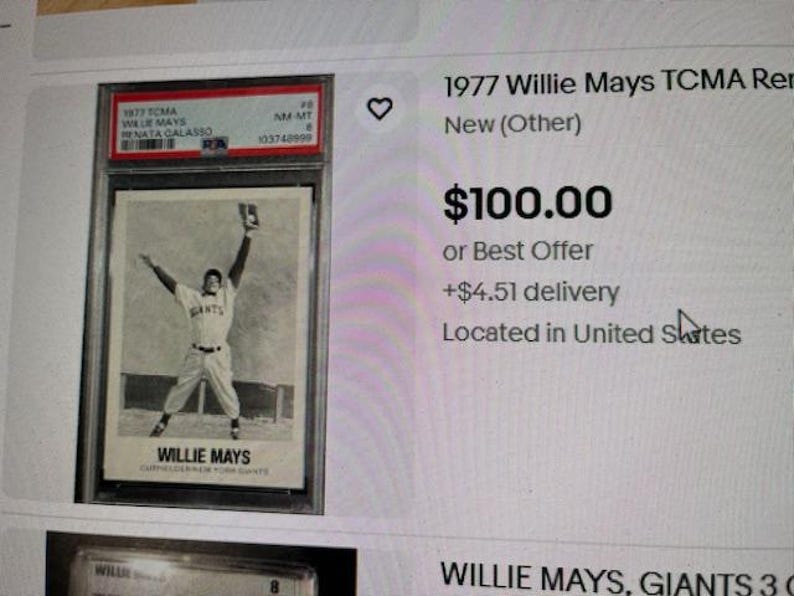Op de afbeelding: Een zwart-wit afbeelding van een honkbalkaart van Willie Mays uit 1977. De kaart toont Willie Mays in een Giants-uniform met zijn armen omhoog. De kaart zit in een beschermende houder.