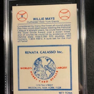 Op de afbeelding: Een honkbalkaart met Willie Mays, een outfielder voor de New York Giants. De kaart bevat informatie over zijn carri&egrave;rehoogtepunten en statistieken, met een logo en adres van Renata Galasso Inc. De kaart zit in een beschermende houder.