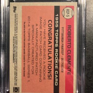 May include: A 1955 Topps Roberto Clemente rookie card, encased in a protective holder. The card features a red and tan background with text that reads "Congratulations!" and details about the card's manufactured patch.