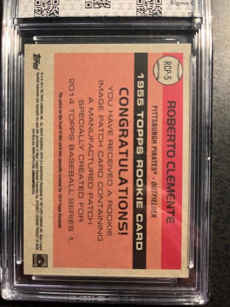 May include: A 1955 Topps Roberto Clemente rookie card, encased in a protective holder. The card features a red and tan background with text that reads "Congratulations!" and details about the card's manufactured patch.