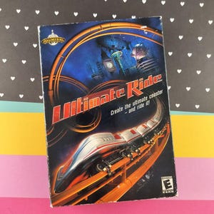 May include: A video game box for "Ultimate Ride" featuring a roller coaster design. The box has a blue background with a futuristic cityscape and a roller coaster train. Text reads "Create the ultimate coaster - and ride it!"