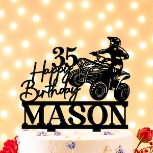 Könnte beinhalten: Ein schwarzer Tortenstecker mit der Silhouette einer Person auf einem Quad. Der Text lautet 35 Happy Birthday MASON. Das Design umfasst eine horizontale Leiste an der Basis mit zwei vertikalen Stiften zum Einstecken in die Torte.