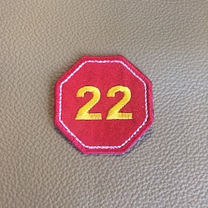 May include: Red octagonal patch with white stitching and the number 22 embroidered in yellow.