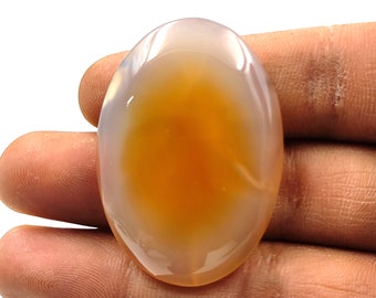 May include: A smooth, oval-shaped agate cabochon with a translucent, milky white exterior and a bright orange center.