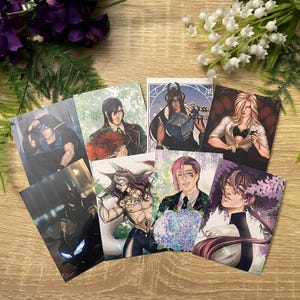 May include: A collection of seven rectangular art prints featuring diverse illustrated characters in various settings, including one with a motorcycle, one with a bouquet of red flowers, and one with a bouquet of blue flowers, all displayed together.