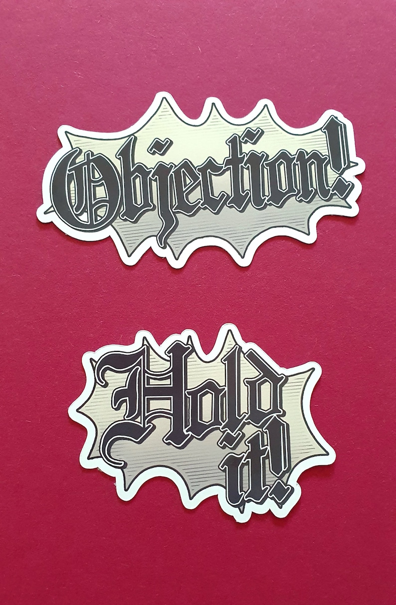 May include: Two white stickers with black text in a comic book style font. The top sticker says "Objection!" and the bottom sticker says "Hold it!"