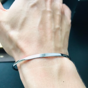 Puede incluir: Un brazalete de plata en la muñeca de una persona.