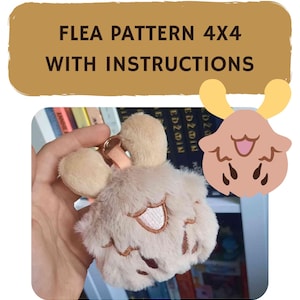 Op de afbeelding: Een zachte, lichtbruine sleutelhanger in de vorm van een stripfiguur met een lachend gezicht en kleine geweien. De sleutelhanger wordt in een hand gehouden. De tekst "FLEA PATTERN 4X4 WITH INSTRUCTIONS" wordt hierboven weergegeven.