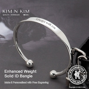 May include: Silver bangle bracelet with a rounded, polished finish. The bracelet has two small balls on the ends and is engraved with the words "Always with you".