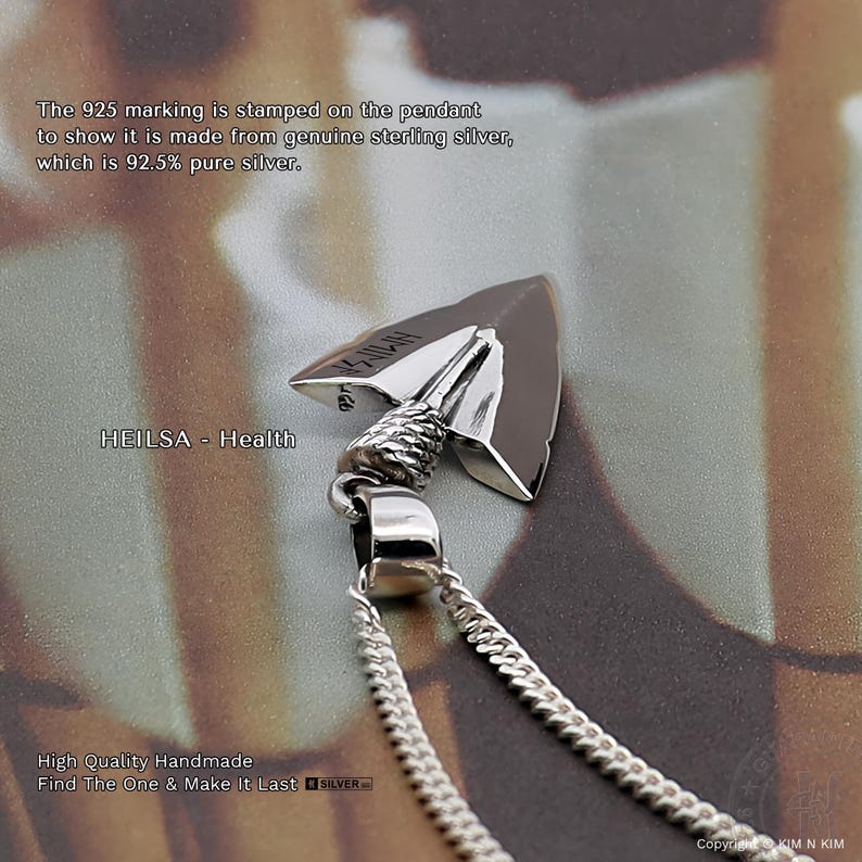 May include: A silver arrowhead pendant on a chain. The pendant features a textured rope-like detail at the top and a smooth, polished surface. The text HEILSA - Health is visible, along with a 925 stamp indicating 92.5% pure sterling silver.