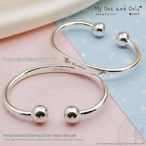 May include: Two polished sterling silver baby bangles with open ends featuring spherical terminals. One bangle is engraved with the text 1st Birthday and the other with God Bless U. The bracelets are presented as personalised silver keepsakes.