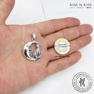 Puede incluir: Colgante de plata con un gato sobre una luna creciente, junto a una moneda de una libra esterlina. El di&aacute;metro de la moneda es de 23,43 mm. El colgante est&aacute; marcado con "925 STERLING SILVER".