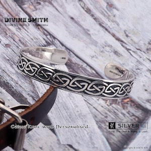 May include: A silver Celtic knot cuff bracelet. The open design features an intricate pattern of interwoven lines. The text "DIVINE SMITH SIGNS & SYMBOLS" and "SILVER" are visible. The text "Celtic Knot with Personalised" is also visible.