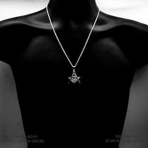 May include: Silver pendant necklace featuring a Masonic symbol with an all-seeing eye. The necklace is 22 inches long and has a curb chain.