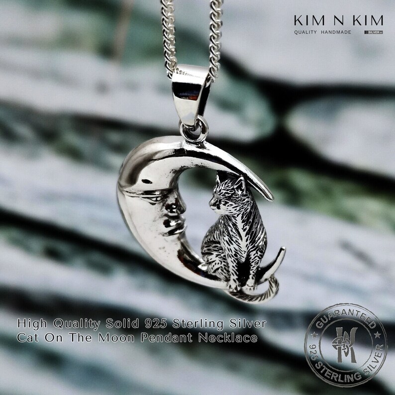 Puede incluir: Un collar con colgante de plata de ley con un dise&ntilde;o de media luna y un gato. El collar cuelga de una cadena de plata. El texto dice "High Quality Solid 925 Sterling Silver Cat On The Moon Pendant Necklace."