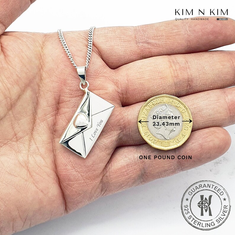 May include: Sterling silver pendant necklace featuring a detailed envelope design with a heart and the inscription "I Love You". The pendant is shown next to a one pound coin for size comparison. The pendant measures 23.43 mm in diameter.