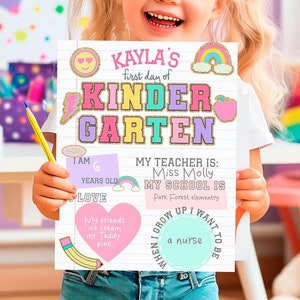 Peut inclure: Une fille tient une pancarte qui dit "Kayla's first day of Kindergarten". La pancarte est décorée d'autocollants colorés et comprend des informations sur son âge, son professeur et son école.