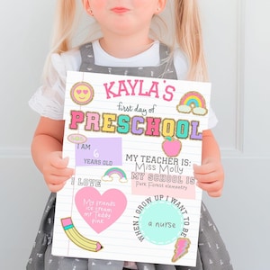 May include: A colorful sign with the text "KAYLA'S first day of PRESCHOOL" and a rainbow, clouds, and a smiling face. The sign also includes the text "I AM 6 YEARS OLD", "I LOVE", "MY TEACHER IS: Miss Molly", "MY SCHOOL IS: Park Forest Elementary", "WHEN I GROW UP I WANT TO BE a nurse".