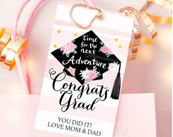 May include: Pink and black graduation gift tag with a floral graduation cap design. The tag says "Time for the next Adventure Congrats Grad You Did It! Love Mom & Dad".