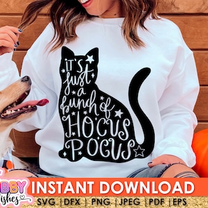 以下が含まれることがあります： 白いスウェットシャツに、黒い猫のシルエットと「It's just a bunch of Hocus Pocus」という白い文字が書かれています。スウェットシャツは小さな白い星で飾られています。