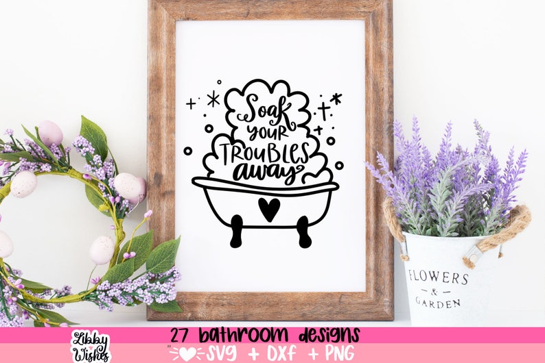 May include: A black and white illustration of a bathtub with bubbles and the text "Soak your troubles away". The illustration is framed in a wooden frame and displayed on a white wall with a potted lavender plant in the foreground.