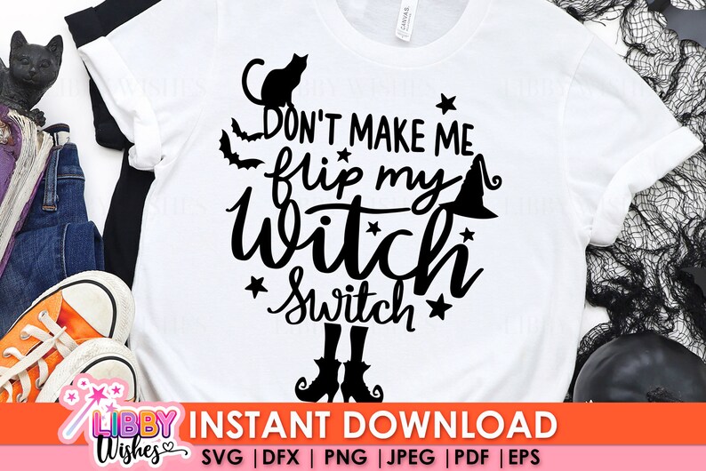 以下が含まれることがあります： 黒い文字で「Don't make me flip my witch switch」と書かれた白いTシャツ。文字の周りは星と、猫と魔女の帽子が黒くシルエットで描かれている。