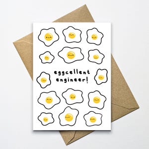 May include: A white card with a black outline of a fried egg with a smiley face. The card has the text "eggcellent engineer!" in black text.