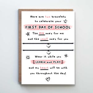 May include: A white card with black and pink text that reads "Here are two bracelets to celebrate your FIRST DAY OF SCHOOL. The BIG one's for me and the small one's for you. Wear it while you LEARN and PLAY and my heart will be with you throughout the day!"