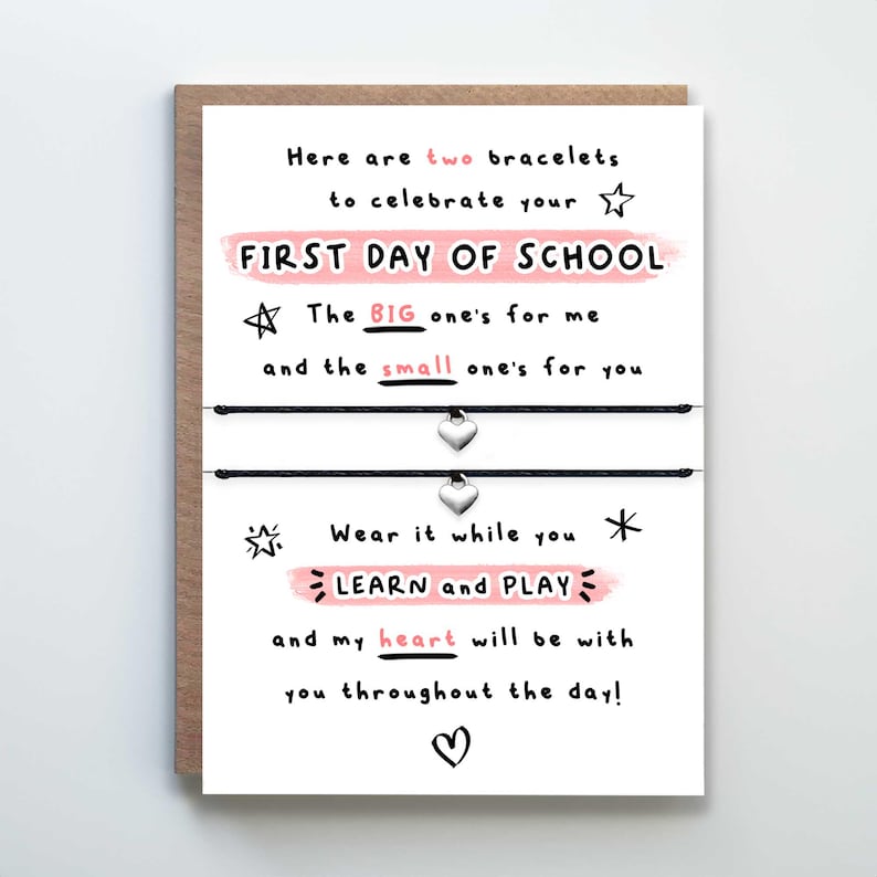 May include: A white card with black and pink text that reads "Here are two bracelets to celebrate your FIRST DAY OF SCHOOL. The BIG one's for me and the small one's for you. Wear it while you LEARN and PLAY and my heart will be with you throughout the day!"