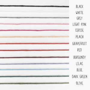 May include: A color chart showing 14 different colors of embroidery floss. The colors are: black, white, grey, light pink, cerise, peach, grapefruit, red, burgundy, lilac, blue, dark green, and olive.