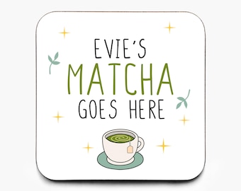 May include: A square white coaster with rounded corners. The text "EVIE'S MATCHA GOES HERE" is in black and green. A cup of matcha tea sits on a light green saucer. Decorative leaves and stars surround the text.