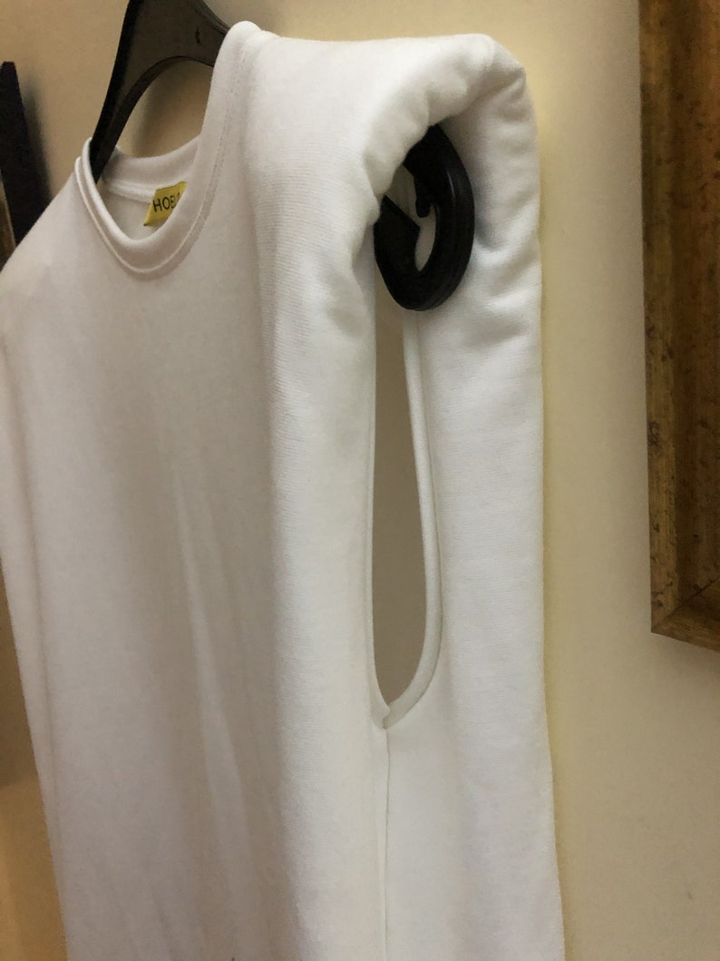 May include: White sleeveless shirt with a yellow tag that says "HOS" hanging on a black hanger.