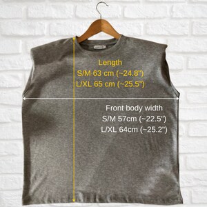 May include: Gray sleeveless shirt with a round neckline and a slightly oversized fit. The shirt has measurements for different sizes: S/M length 63 cm (24.8 inches), L/XL length 65 cm (25.5 inches), S/M front body width 57 cm (22.5 inches), L/XL front body width 64 cm (25.2 inches).