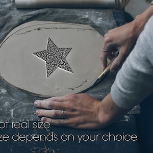 Peut inclure: Une pièce d'argile grise, plate et circulaire, présentant une découpe en forme d'étoile avec un motif de feuilles complexe. L'argile est façonnée avec un outil en métal. Le texte "Not real size" et "Size depends on your choice" est visible.