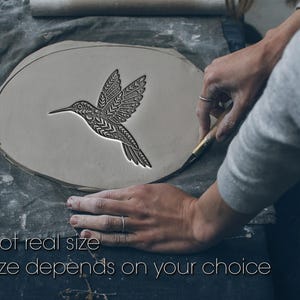 Peut inclure: Une pièce d'argile gris clair avec un motif de colibri détaillé en cours de sculpture. Le texte "Not real size" et "Size depends on your choice" est au bas de l'image. Le colibri a des motifs complexes sur les ailes et le corps.