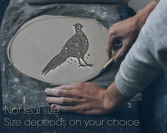 May include: A gray ceramic piece with a detailed pheasant design. The bird is intricately carved with floral and star patterns. The text "Not real size. Size depends on your choice" is at the bottom.