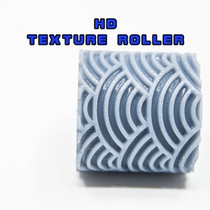 Op de afbeelding: Een grijze, getextureerde roller met een herhalend patroon van gebogen lijnen. De roller is gelabeld met "HD TEXTURE ROLLER".