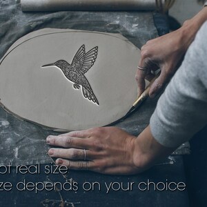 May include: A gray clay piece with a detailed hummingbird design being crafted. The hummingbird is black with intricate patterns. Text at the bottom reads "Not real size. Size depends on your choice."