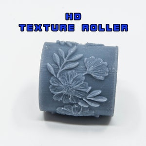 Könnte beinhalten: Eine graue, strukturierte Rolle mit einem Blumenmuster. Die Rolle ist mit "HD TEXTURE ROLLER" beschriftet.