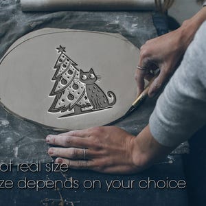 以下が含まれることがあります： クリスマスツリーと猫のデザインが施された灰色の陶器。木にはオーナメントと星が飾られています。猫は木の隣に座っています。画像内のテキストは「Not real size. Size depends on your choice.」と表示されています。