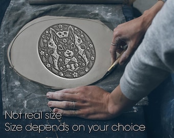 May include: A flat, oval-shaped piece of gray clay featuring an embossed, detailed illustration of a squirrel holding an acorn, surrounded by floral and leaf patterns. The text "Not real size. Size depends on your choice" is visible below.