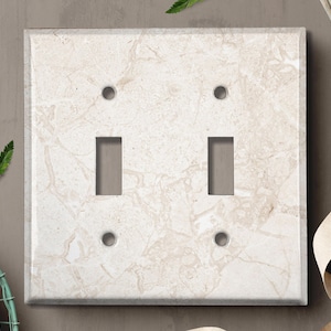 May include: A white light switch cover with a marble pattern. The cover has two toggle switches and four screw holes.