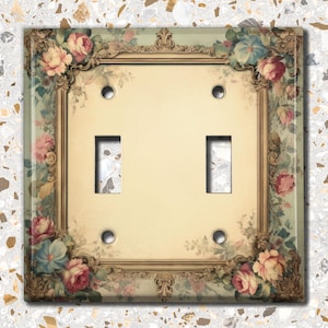 May include: A double light switch cover with a vintage floral design. The cover features a gold frame with ornate details and a light green background. The floral design includes pink, red, and blue flowers.