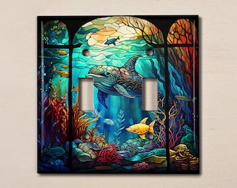 May include: A stained glass style light switch cover featuring a blue whale swimming through a colorful underwater scene with coral, seaweed, and fish.