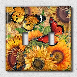 May include: A light switch cover featuring a colorful floral design with butterflies. The design includes sunflowers, butterflies, and other floral elements in shades of yellow, orange, red, and brown.